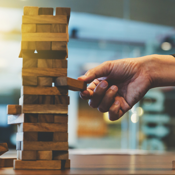 Hand removing a wooden block from a Jenga game