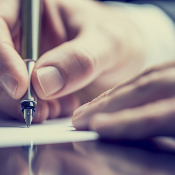 Close up of a hand holding a pen to paper