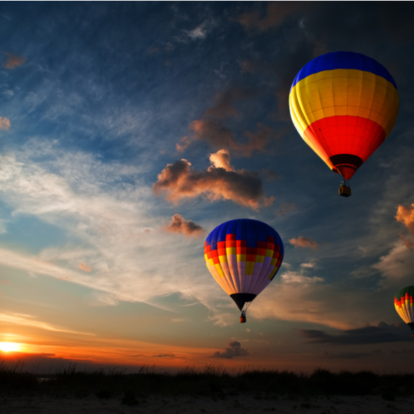 Three colourful hot air balloons flying at sunrise