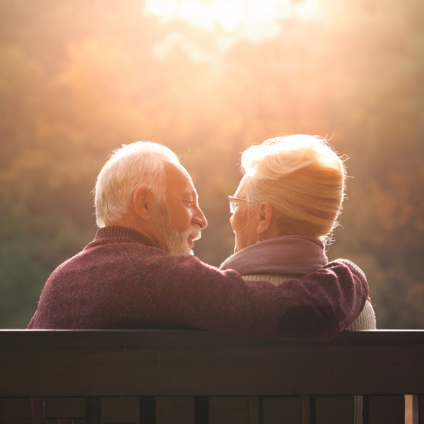 Senior couple sitting on a park bench in autumn