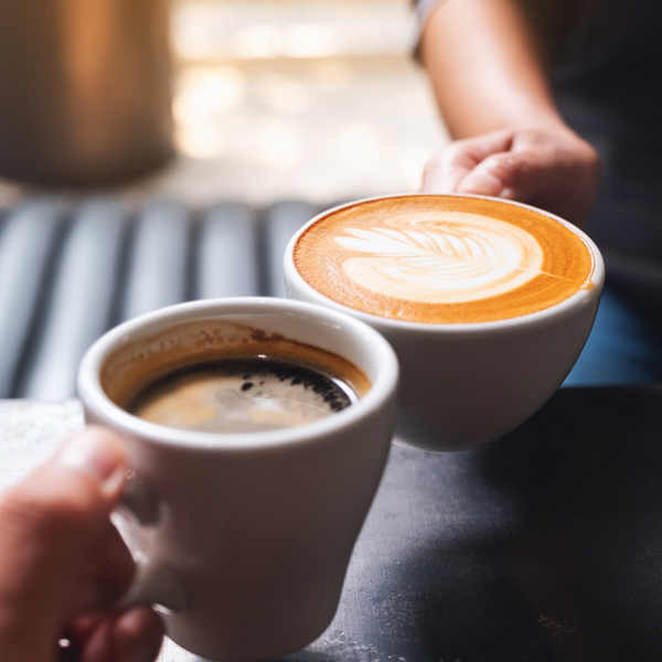 Close up of two people holding coffee cups in a cafe