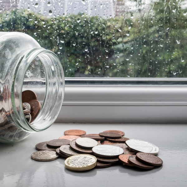 A jar of money tipped over with a rainy day in the background