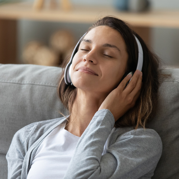 A woman wearing headphones as she sits on a sofa