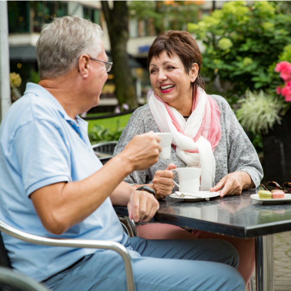 An older couple enjoying a cup of coffee outside at a café.