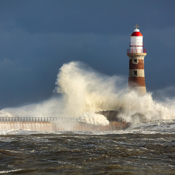 waves crashing against a lighthouse in a storm