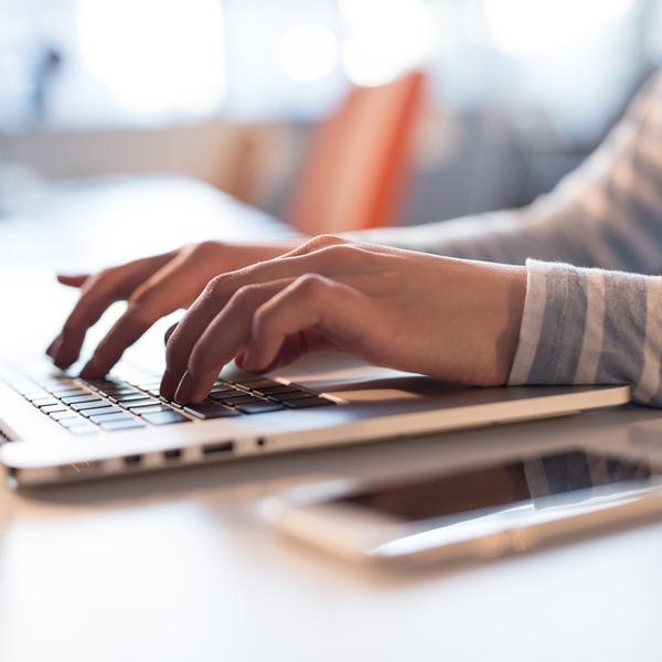 A young woman typing on a laptop in an office space.