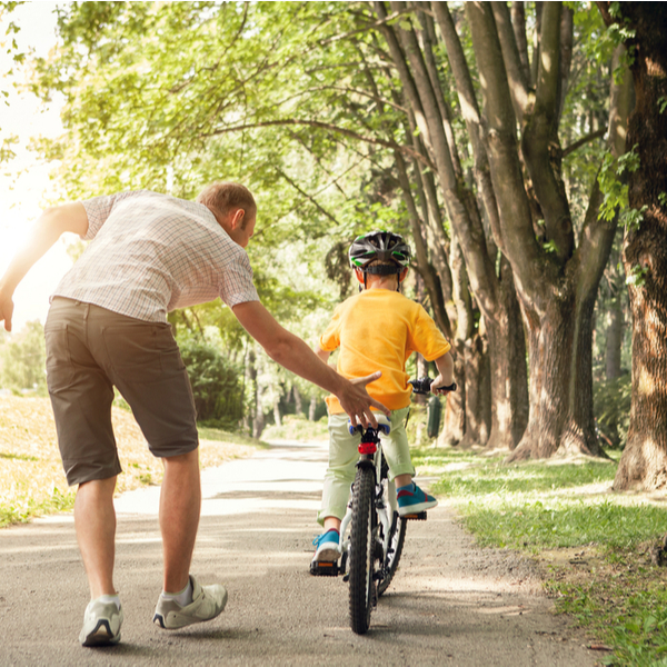 A father teaching his young son to ride a bike.