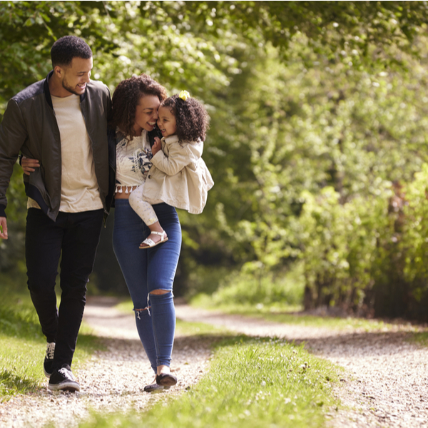 A family of three walking through some woods