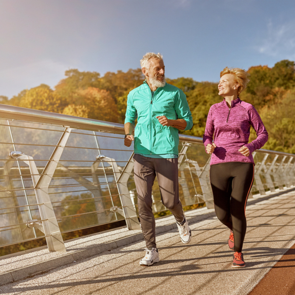 A mature couple jogging across a bridge.