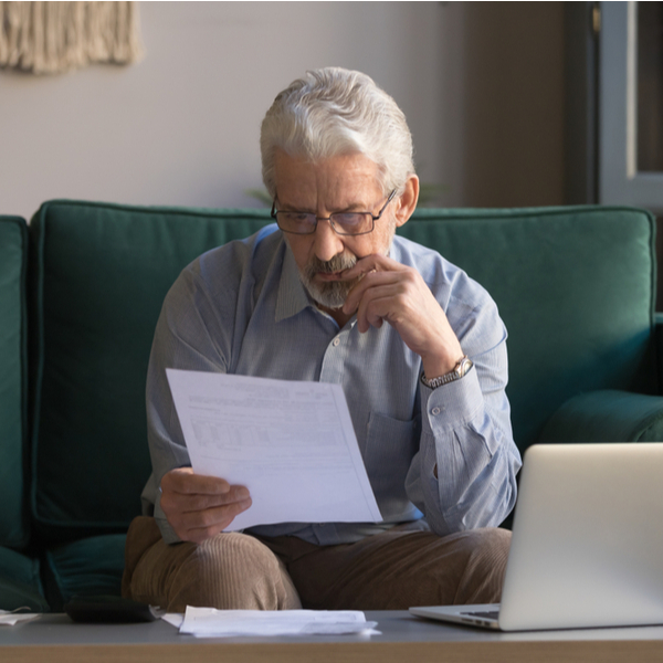 An older man reviewing some paperwork at home.