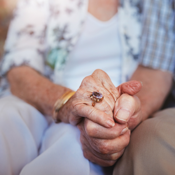 A close up of an elderly couple holding hands.