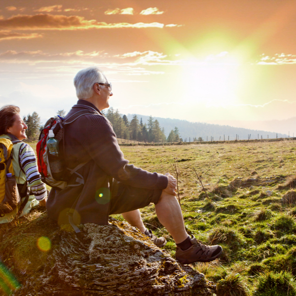 An older couple watching the sunrise on a hike.