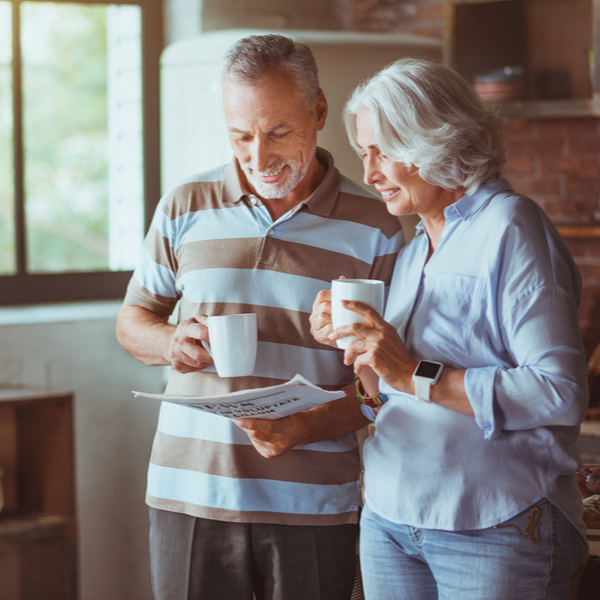 A couple drinking coffee and looking at some paperwork.