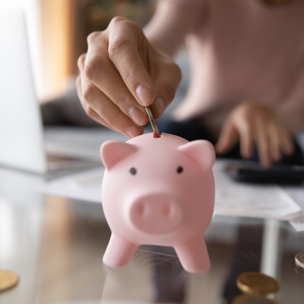 A woman placing money in a piggy bank.