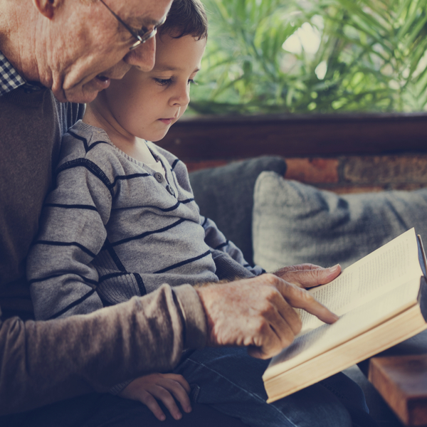 A grandfather reading a book with his grandson.