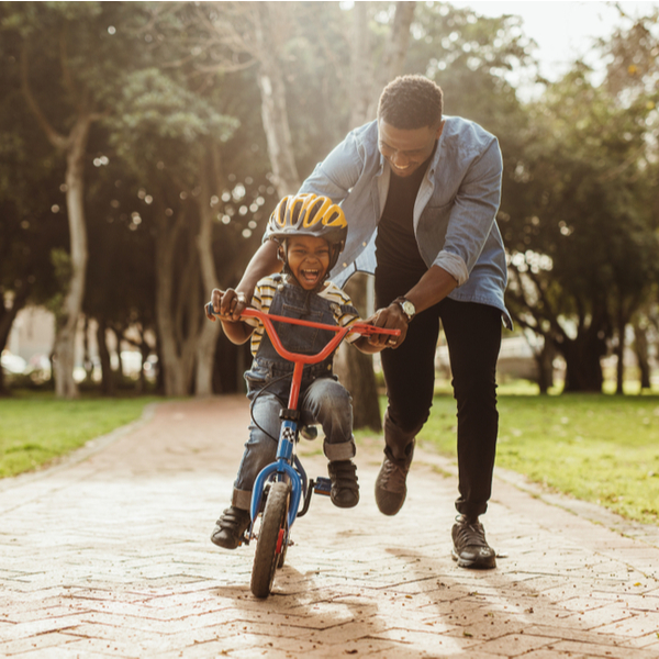 A father teaching a child to ride a bike.