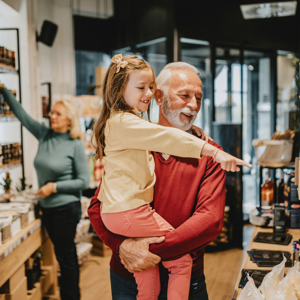A grandfather grocery shopping with his granddaughter.