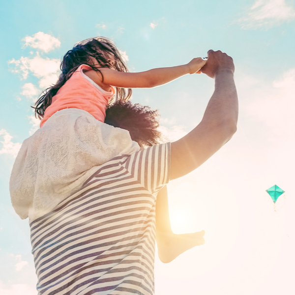 A father with his young daughter sitting on his shoulders.