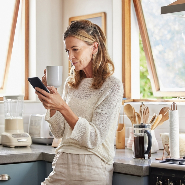 A woman drinking a coffee while looking at her phone.