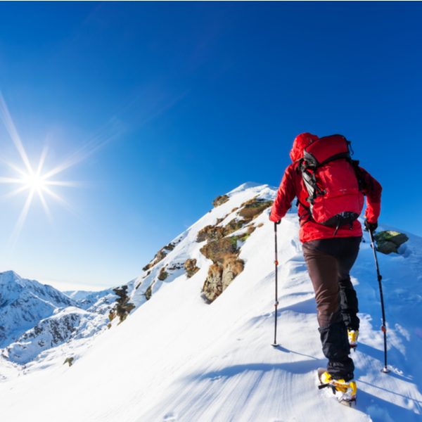 A climber at the top of a snowy peak.