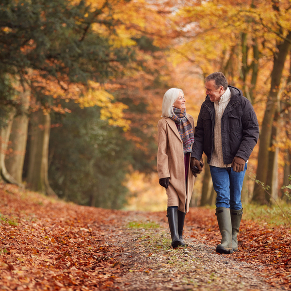 An older couple walking through woodland.