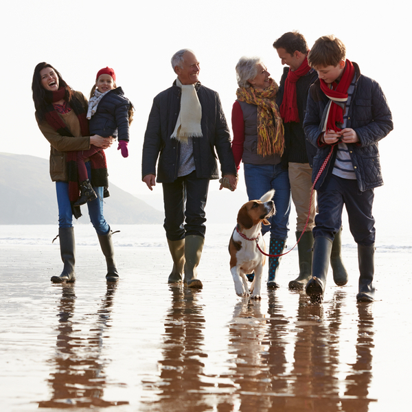 A multi-generation family walking together on a beach.