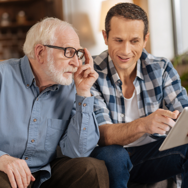 Young man showing his elderly father something on a tablet