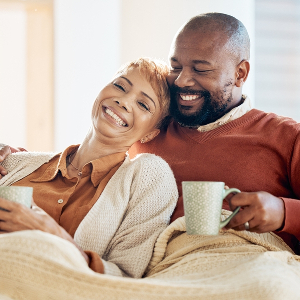 A couple laughing together while drinking coffee.