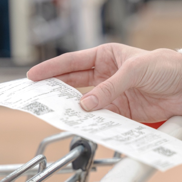 A woman looking at a receipt while shopping.
