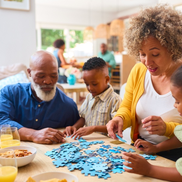 Grandparents doing a jigsaw with their two grandchildren.