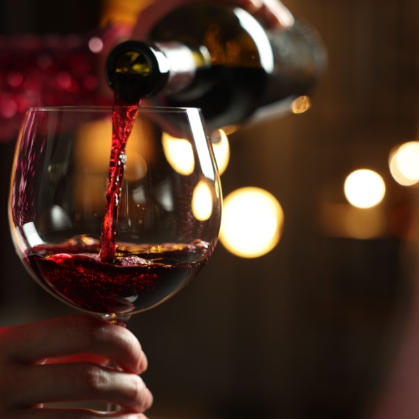 Someone pouring a glass of red wine.