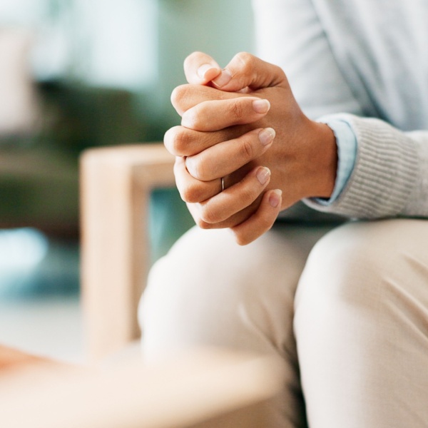 A woman sitting with her hands clasped.