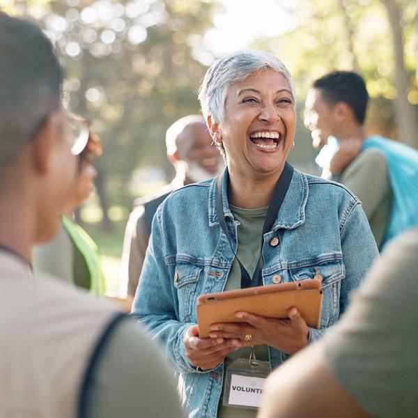A woman with a clipboard volunteering at an event in a park.