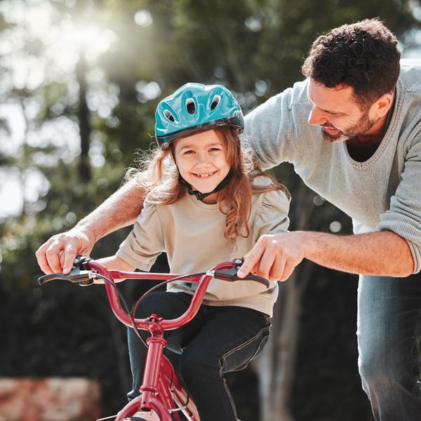 A father teaching his daughter to ride a bike.