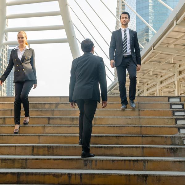 Three office workers crossing on some steps.