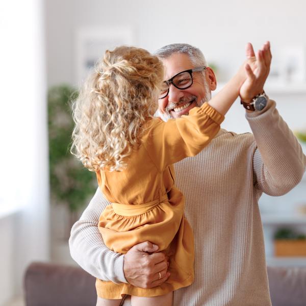 A grandfather playing with his granddaughter at home.