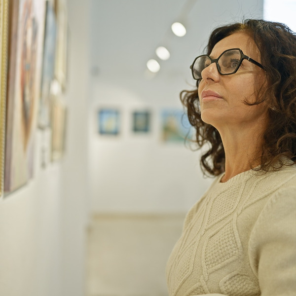 A woman looking at a painting in an art gallery.