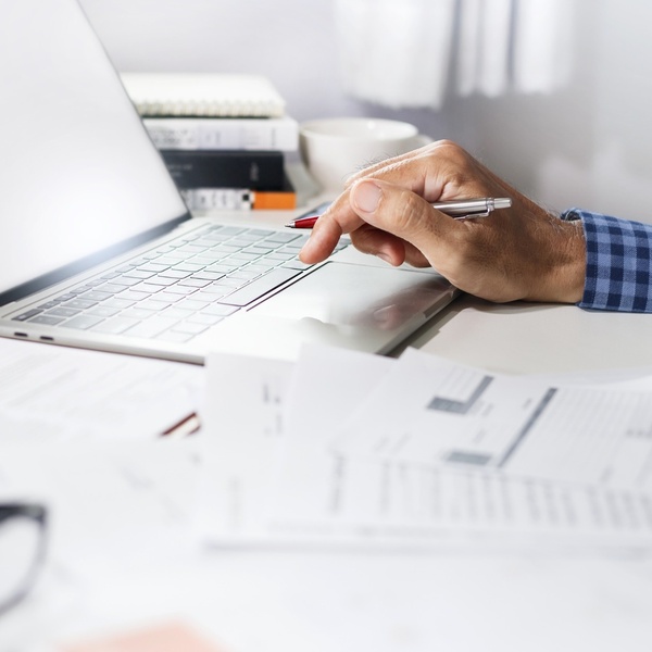 Man’s hands at a laptop, with financial paperwork