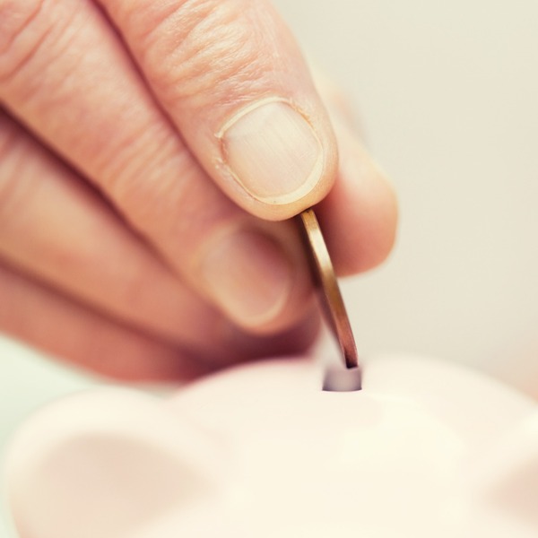 A person putting a coin into a money box.