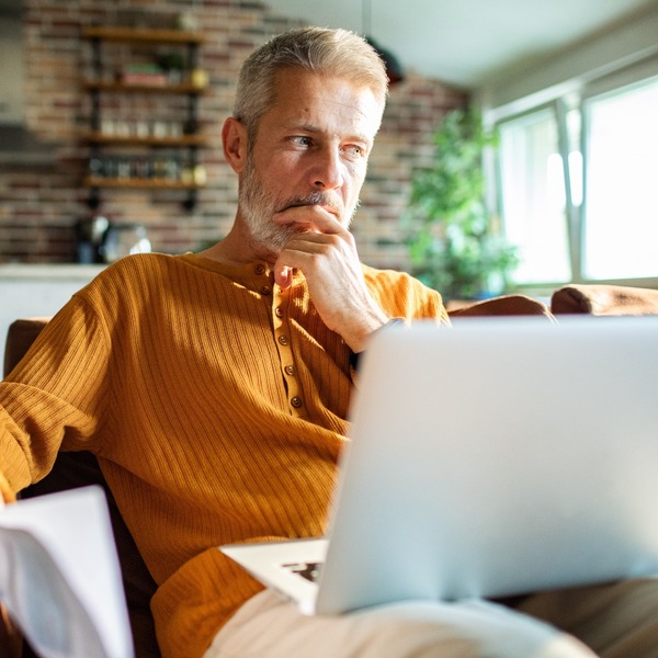 A man in his 50s thinking while using a laptop