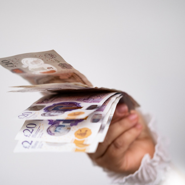A hand holding UK bank notes.