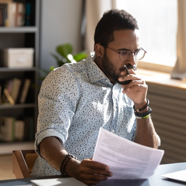 A man looking contemplatively at a desk.