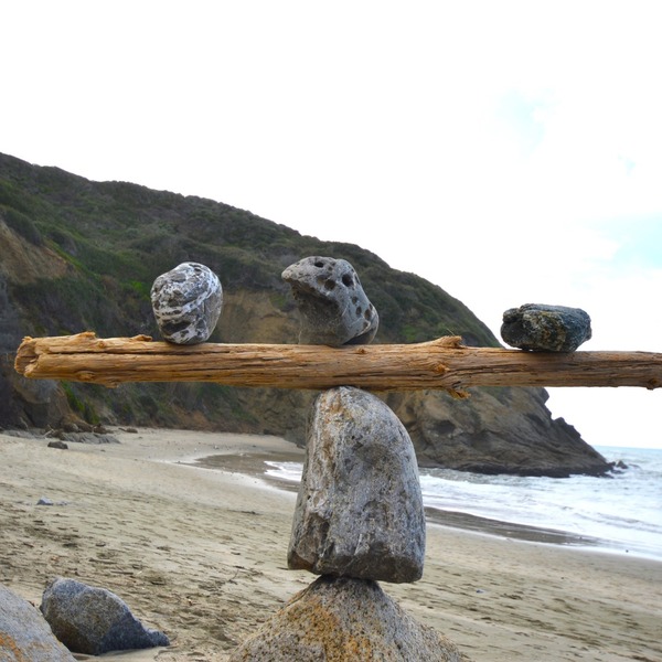 Rocks balancing on log on top of another rock