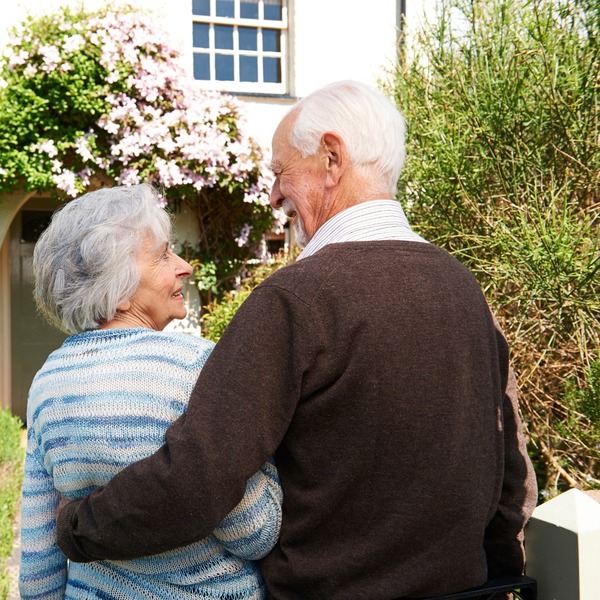 Rear view of senior couple outside pretty cottage